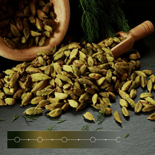 Cardamom seed pods spill from a wooden ladel onto a grey stone benchtop