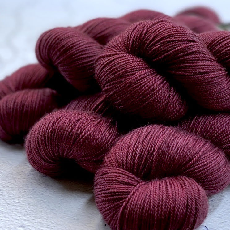 Hand dyed yarn. Rich saturated plum red, cool red, semi solid, hand dyed yarn on Merino Silk Yak fingering weight 4 ply yarn.